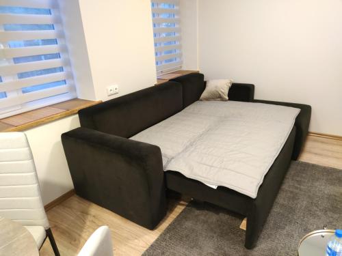 ein schwarzes Bett in einem Zimmer mit Fenster in der Unterkunft Shanghai Banzai New Apartment Vilnius in Vilnius