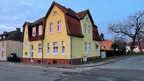 a yellow house with a brown roof on a street at Alte Post - Erdgeschoß in Gützkow