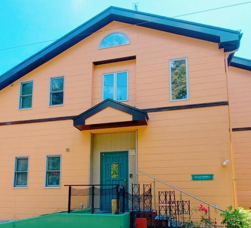 a orange house with a green door at Second House Plus 1組貸し切りのペンション A one group booking per day lodging house in Nikko