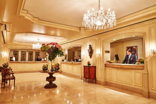 a hotel lobby with a reception desk and a chandelier at Steigenberger Icon Frankfurter Hof in Frankfurt