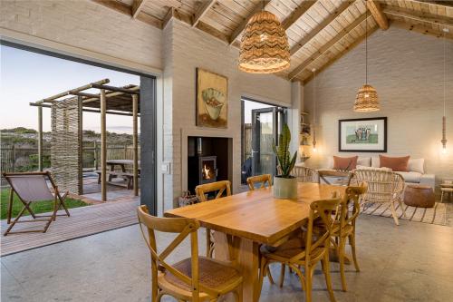 a dining room and living room with a wooden table and chairs at Romansbaai Collection in Gansbaai