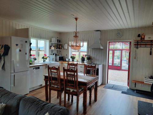 a kitchen with a table and chairs and a refrigerator at Gårdslägenhet nära Göteborg in Alvhem