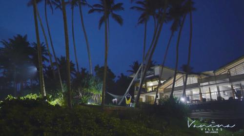a building with palm trees in front of it at night at Vanina Villas in Matara