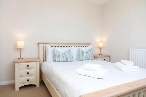 1 dormitorio con 1 cama blanca y 2 mesitas de noche en Alpine Cottage, en Bigbury-on-Sea
