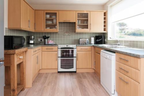 a kitchen with wooden cabinets and a white stove top oven at Alpine Cottage in Bigbury on Sea
