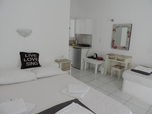a white living room with a white couch and a kitchen at Three Harites in Perissa