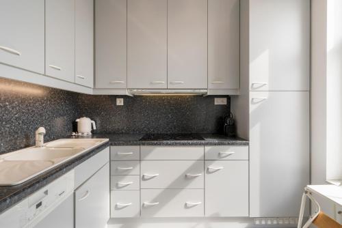 a kitchen with white cabinets and a sink at Residence Palace Style app in a unique building in Zeebrugge
