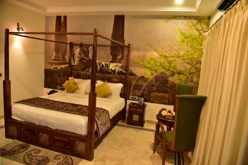 a bedroom with a canopy bed and a table with a chair at Clarks Safari Ranthambore in Khilchipur