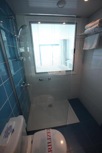 a bathroom with a shower and a toilet and a window at Anonymous Beach Hotel (Adults 16+) in Ayia Napa
