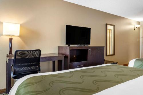 a hotel room with a bed and a flat screen tv at Quality Inn & Suites Escanaba North in Escanaba