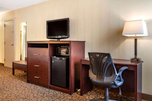 a hotel room with a desk with a television and a chair at Quality Inn & Suites Escanaba North in Escanaba