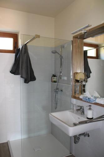 a white bathroom with a shower and a sink at Tündérkert Panzió Őrség in Viszák