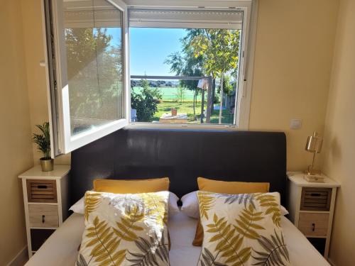 a bedroom with a bed with two pillows and a window at La Casita De Campo. Relax y Naturaleza in El Casar de Talamanca
