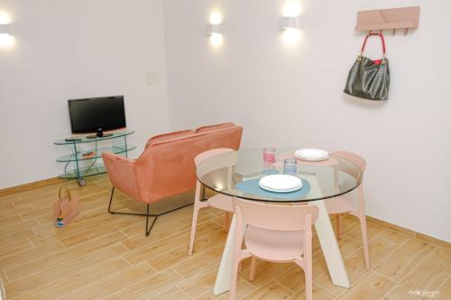 a room with a glass table and chairs and a television at Appartamento Nonna Lina in Custonaci