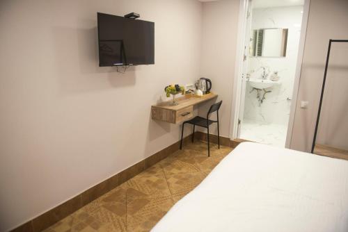 1 dormitorio con cama, escritorio y lavamanos en Homey en Tiflis