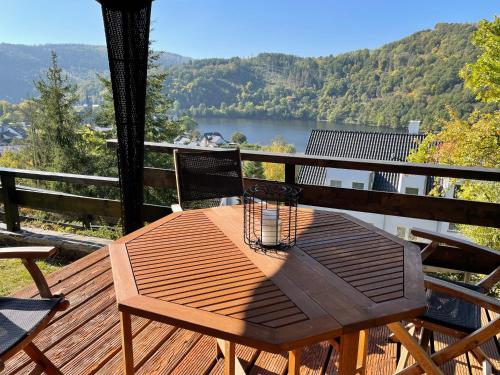 a wooden table on a deck with a view of a lake at Ferienhaus Sonnendeck 2 in Simmerath