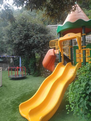 a playground with a yellow slide in a yard at Welcomhotel by ITC Hotels, Tavleen, Chail in Chail