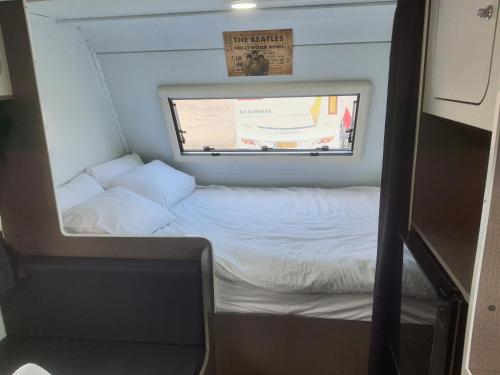 a small bed in a small room with a window at Ein Gedi caravan by Dory caravan in Ein Gedi