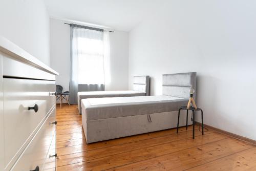 a white bedroom with a bed and a wooden floor at Avalon apart 2 in Legnica