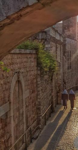 two people walking down a street with umbrellas at New Citadel Hostel in Jerusalem