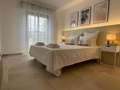 une chambre avec un grand lit blanc avec une fenêtre dans l'établissement Domaine D'Ahmosis, modern 2 bedrooms refurbished apartment, f3 moderne fraichement rénové, au Cannet