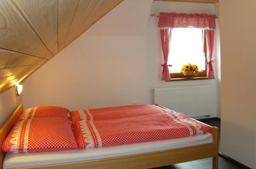 a bed with an orange comforter in a room at Penzion a restaurace U Maryny in Bocanovice