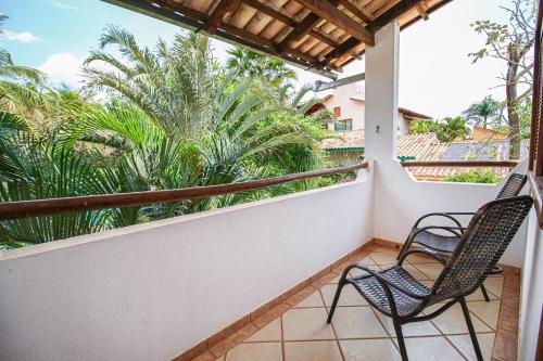 a balcony with two chairs and palm trees at Pousada Flores do Cerrado in Pirenópolis