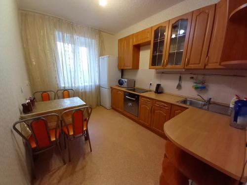 スィクティフカルにあるСomfort Apartment Radugaのキッチン(木製キャビネット、テーブル、椅子付)