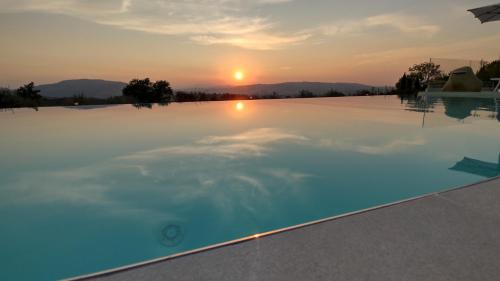 a swimming pool with a sunset in the background at La Maggiolina Country House in Montelabbate