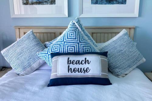 a bed with blue and white pillows on it at Lasalle holiday home (Sun, Beach, Views, Fun for everyone!) in Plettenberg Bay