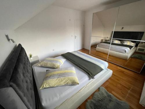 1 cama blanca grande en una habitación con espejo en Komfort Apartman Bilivano, en Zagreb