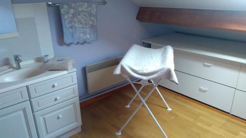La salle de bains est pourvue d'un lavabo et d'une serviette sur une chaise. dans l'établissement LA PETITE MAISON, à Saint-Loup-Géanges