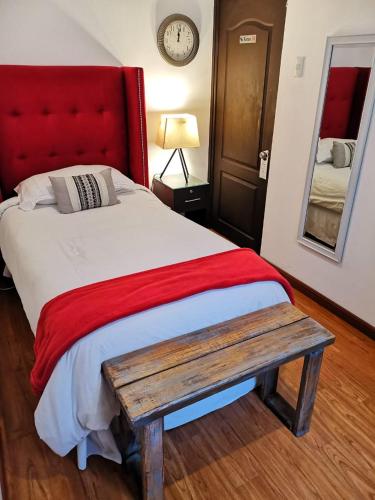 a bedroom with a bed with a red headboard and a bench at Meraki Boutique Hotel in Guatemala