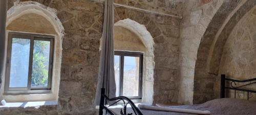 a bedroom with two windows in a stone wall at New Citadel Hostel in Jerusalem