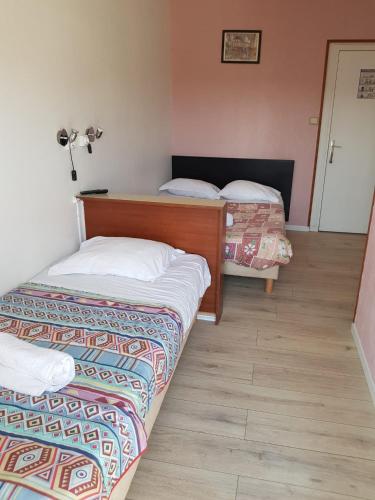 two beds in a small room with at Hotellerie Normande in Dozulé