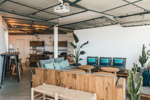a living room with a couch and tables and cactus at MUTE Hostel Porto Covo in Porto Covo