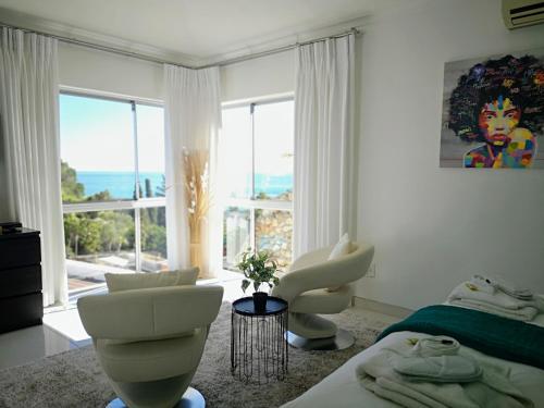a bedroom with white furniture and a large window at Diamond House Guesthouse in Cape Town