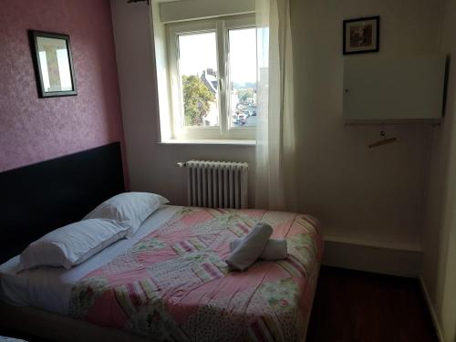 a small bedroom with a bed with a window at Hotellerie Normande in Dozulé