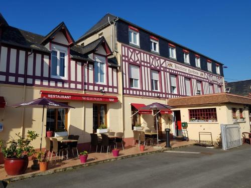 a building with tables and chairs in front of it at Hotellerie Normande in Dozulé