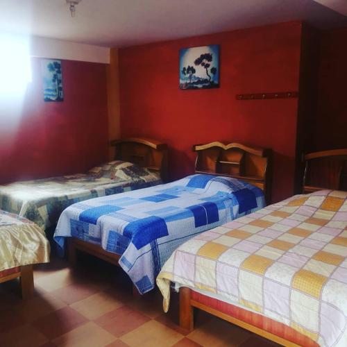 two beds in a room with red walls at Hostal Puerto Alegre in Copacabana