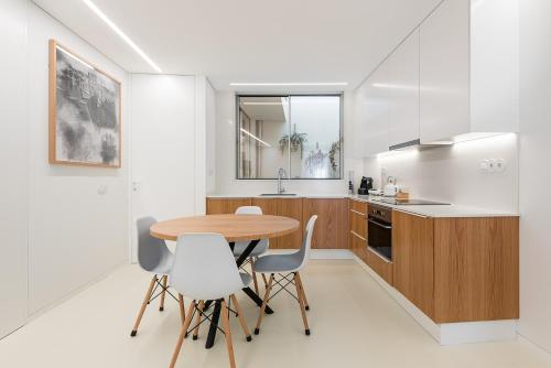 a kitchen with a wooden table and white chairs at Lidador 116 Apartments in Vila do Conde