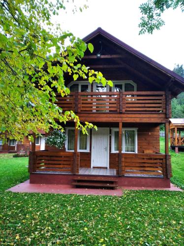 Cabaña de madera con porche y puerta blanca en Катерина, en Rozhanka Nizhnyaya