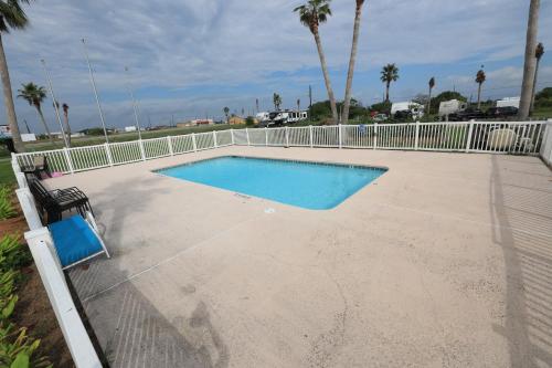 een zwembad op een betonnen patio met een wit hek bij Coastal Bend at Seadrift, Motel & RV Park in Seadrift