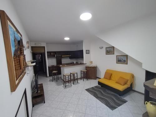sala de estar con sofá amarillo y cocina en Le Casette di Franco & Anna en Asís