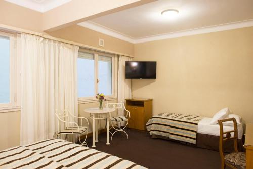 a hotel room with two beds and a table and a window at Hotel Astor in Mar del Plata