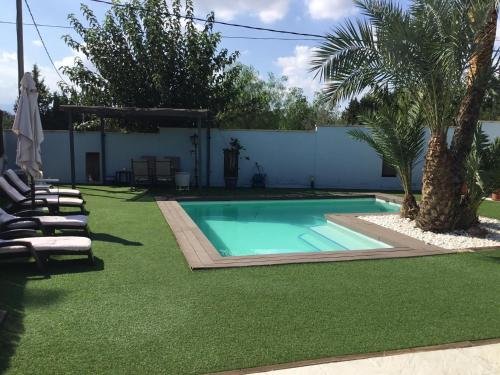 a swimming pool in a yard with chairs and trees at Relax en la huerta de Murcia in Murcia