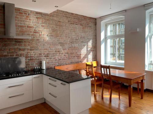 a kitchen with a table and a brick wall at Uroczy apartament 97m2 w samym centrum Wrocławia in Wrocław