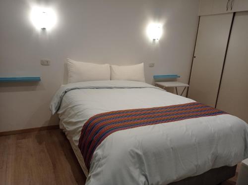 a bedroom with a large white bed with two lights at La Casa de Justi in Huancayo