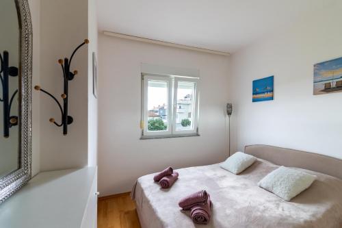 a white bedroom with a bed with a window at Apartment Ben1 in Pula