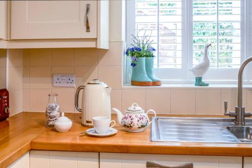 a kitchen counter with a sink and some cups and vases at The Old Stables in Tetbury
